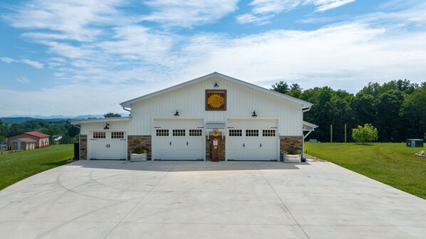 A large, white building with two garage doors, a sign reading "Sunflower Feed," and a paved driveway. - The Sunflower Barn (Alexander)