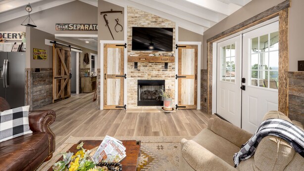 A spacious living room with a stone fireplace, leather sofas, and a wooden floor.