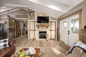 A spacious living room with a stone fireplace, leather sofas, and a wooden floor. - The Sunflower Barn (Alexander)
