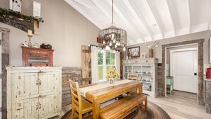 A rustic dining area with a wooden table, benches, and a chandelier.