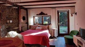 A bedroom with a bed, a television, a chair, a table, and a window. - La Grange- Historic flair and modern comfort in the midst of nature (Sourbrodt, Waimes (Belgien))