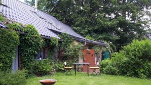 A house with a tiled roof, a brick wall, and a garden with a table and chairs. - La Grange- Historic flair and modern comfort in the midst of nature (Sourbrodt, Waimes (Belgien))