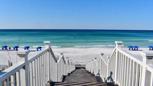 A wooden staircase leading to a beach with white railings and blue umbrellas. - Only 361 Feet to Beach Access in Seaside, King Primary & Renovated + 2 Bikes (Santa Rosa Beach Fl)