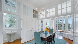 A spacious dining area with a large table, chairs, and a chandelier. There is a white sink and a window with blinds. - Only 361 Feet to Beach Access in Seaside, King Primary & Renovated + 2 Bikes (Santa Rosa Beach Fl)