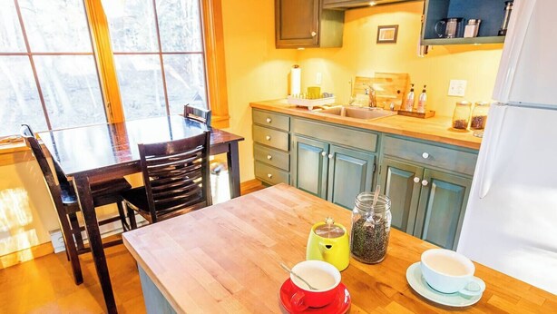 A kitchen with wooden countertops, a dining table, and chairs. There are jars and cups on the counter. - Historic Hudson Valley Farmhouse w/ Sauna in Stone Ridge Hamlet (Stone Ridge)
