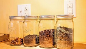 Four glass jars with different contents on a wooden surface, with an electrical outlet in the background. - Historic Hudson Valley Farmhouse w/ Sauna in Stone Ridge Hamlet (Stone Ridge)