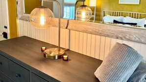 A bathroom with a wooden vanity, a round mirror, a wall-mounted light fixture, and a towel on the counter. - Historic Hudson Valley Farmhouse w/ Sauna in Stone Ridge Hamlet (Stone Ridge)