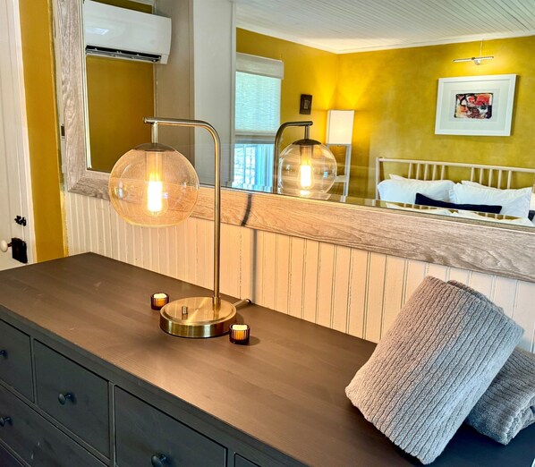 A bathroom with a wooden vanity, a round mirror, a wall-mounted light fixture, and a towel on the counter.