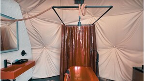A room with a large, orange bathtub, a sink, and a mirror. - Dome 3: Modern Boho Hideaway (South Haven)