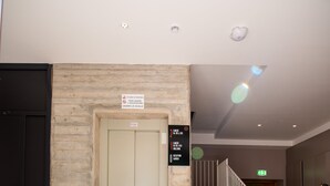 A hotel entrance with a marble wall, a door, a staircase, and a black doormat with the hotel's name. - Palazzo San Giovanni (Cava de' Tirreni)