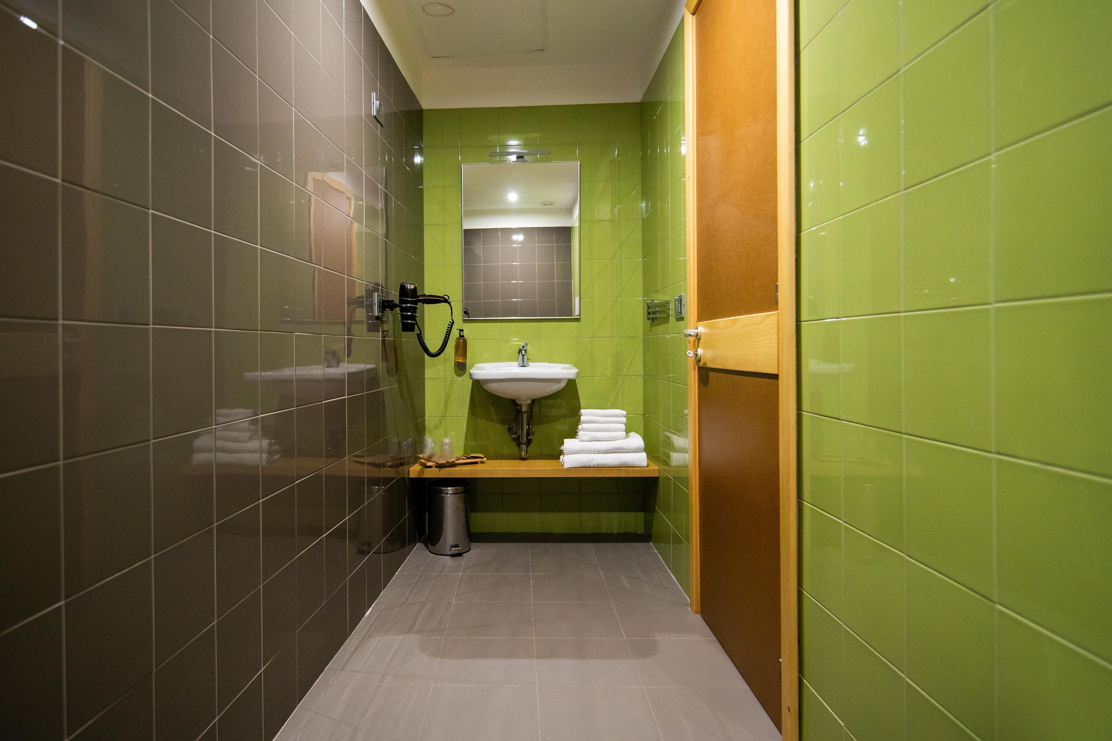 Un baño con paredes verdes, un lavabo blanco y un espejo encima.