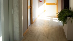 A hallway with a wooden floor, a door labeled '205', and a fire extinguisher on the wall. - Palazzo San Giovanni (Cava de' Tirreni)