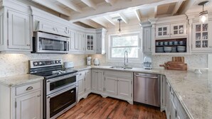 A kitchen with white cabinetry, a stainless steel dishwasher, a double oven, and a microwave. - Stillwater Lakehouse • 20 Acre Lakefront • Sandy Beach • Dock • Firepit! (Port Carling)