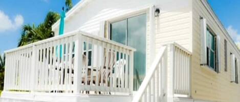 A white mobile home with a balcony and a staircase leading to the entrance.