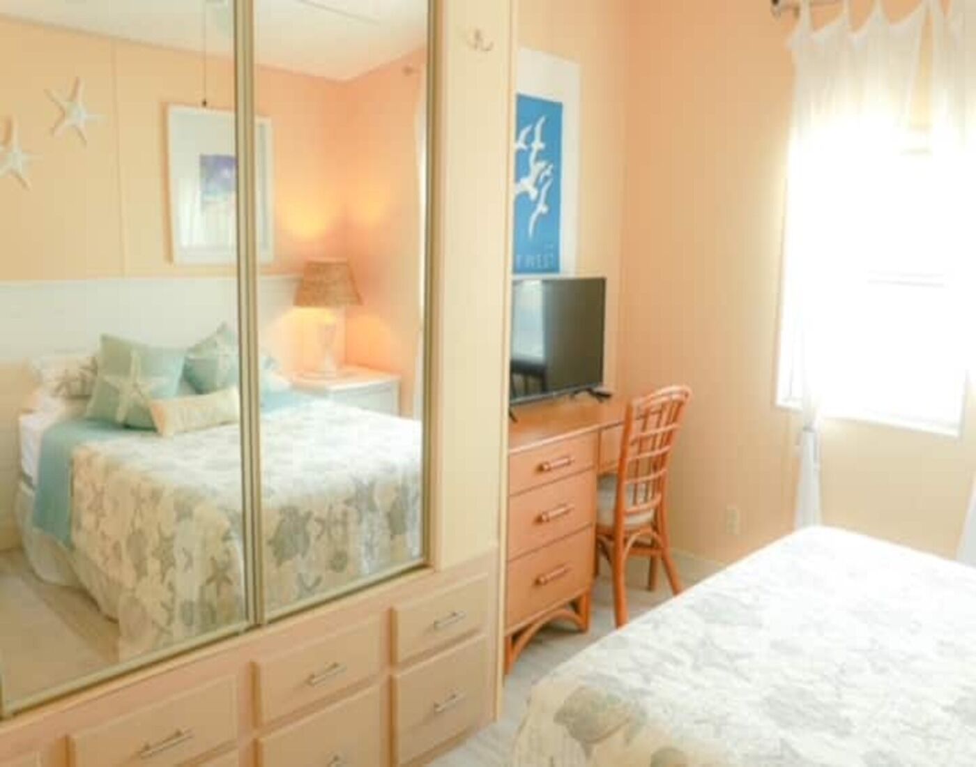 A bedroom with a bed, a desk, a chair, a dresser, and a television.