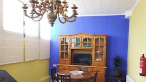 A dining area with a wooden cabinet, a television, and a chandelier. - Mas Guilló Nursery (Sant Quintí de Mediona)