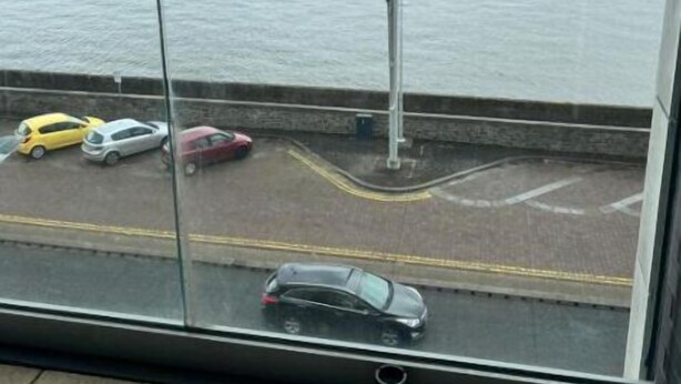 A balcony with a view of a body of water and parked cars. - Luxury 2 bed waterfront apartments (seaview) (Dundee)
