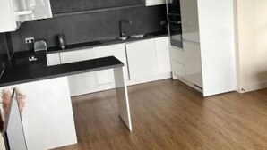 A modern kitchen with white cabinets, a black countertop, and a wooden floor. - Luxury 2 bed waterfront apartments (seaview) (Dundee)