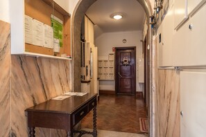 Enter a welcoming hallway with a desk, bulletin board, and cabinets, leading to a door with a decorative wreath.