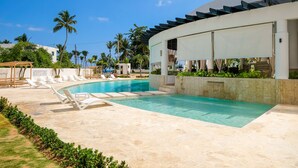 A pool area with lounge chairs, a covered seating area, and palm trees. - Amar'e Aparthotel & Spa (Las Terrenas)