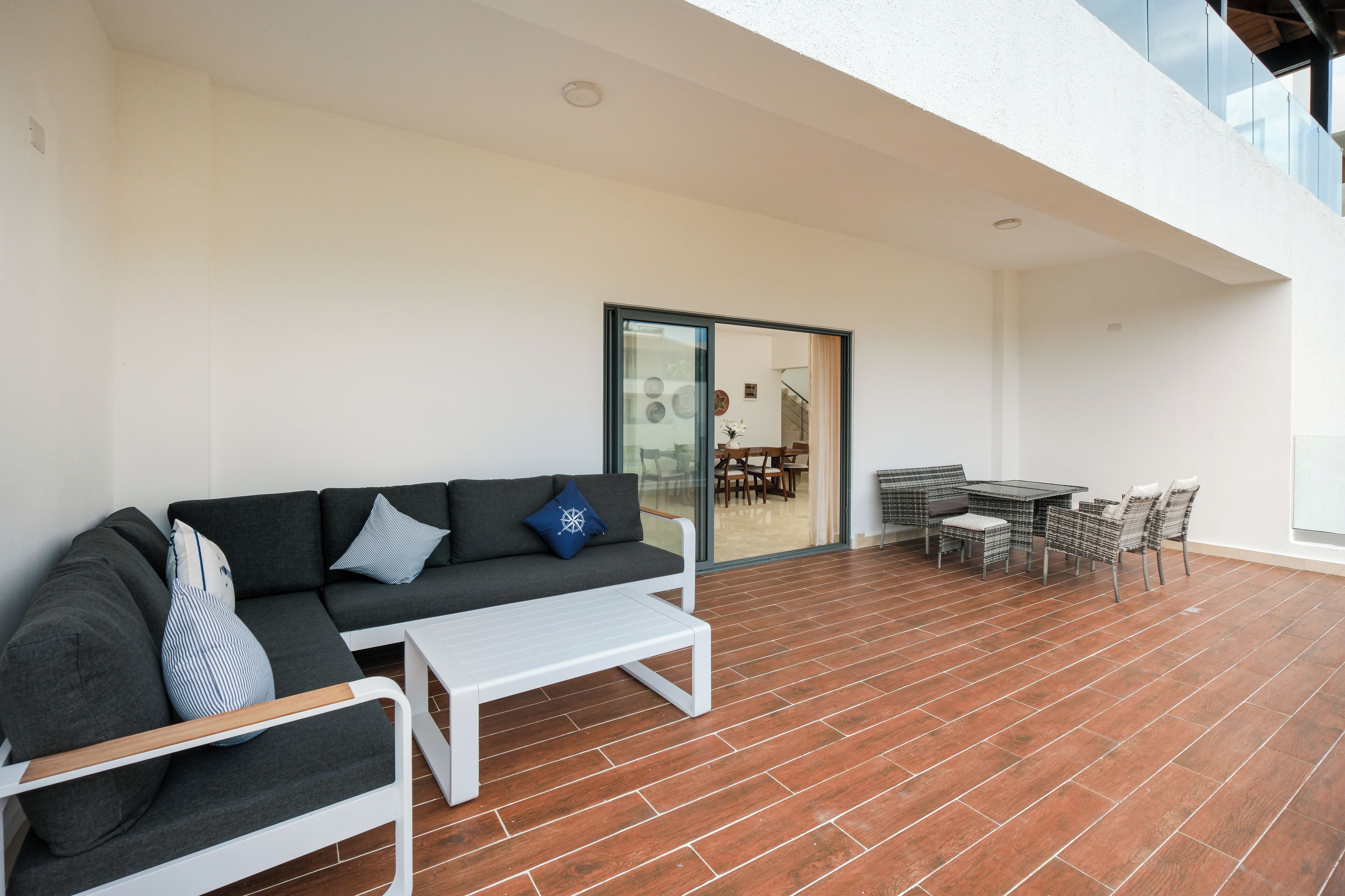 Un espacio al aire libre moderno con sofás, una mesa pequeña y un comedor.