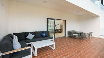 Un espacio al aire libre moderno con sofás, una mesa pequeña y un comedor.