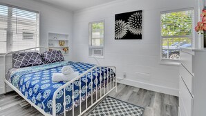 Une chambre à coucher avec un lit, un ventilateur de plafond et une fenêtre avec des stores.