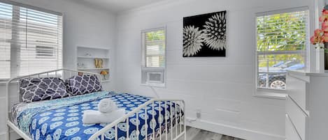 A bedroom with a bed, a ceiling fan, and a window with blinds.