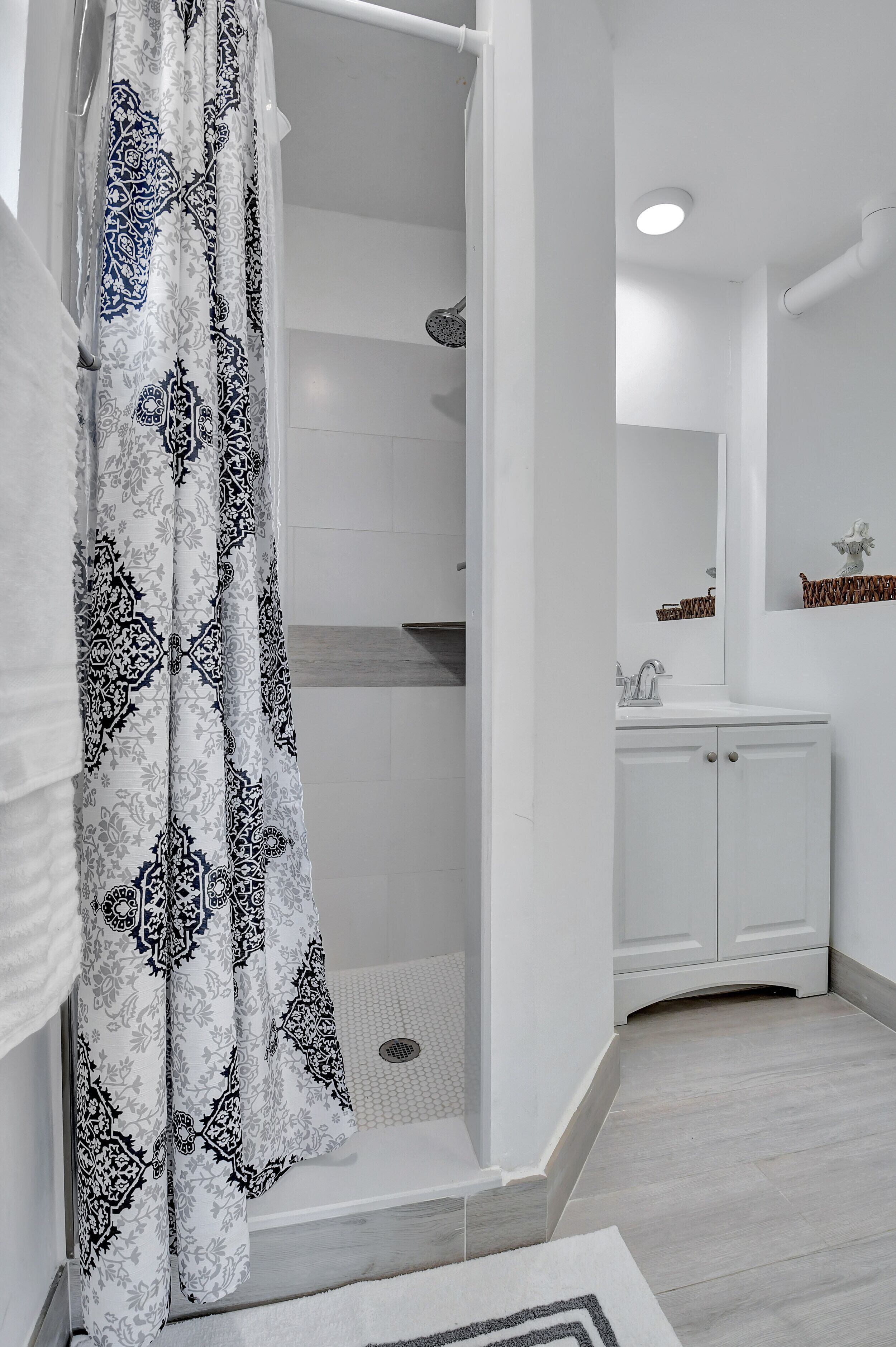 Un baño con ducha, lavabo y espejo.