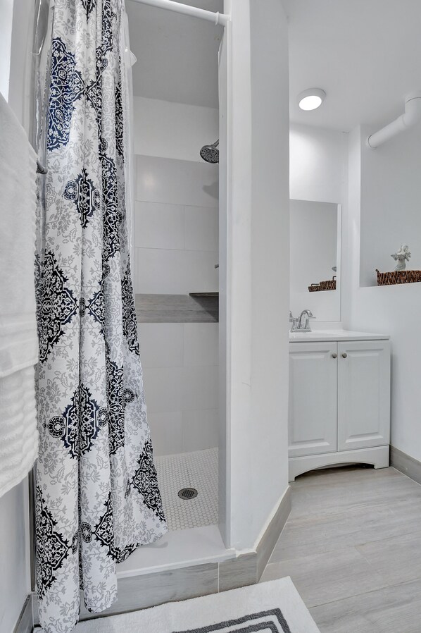 A bathroom with a shower, a sink, and a mirror. - AMAZING PRIVATE COSY HOUSE, FENCED YARD, NEW, PETS (Delray Beach)