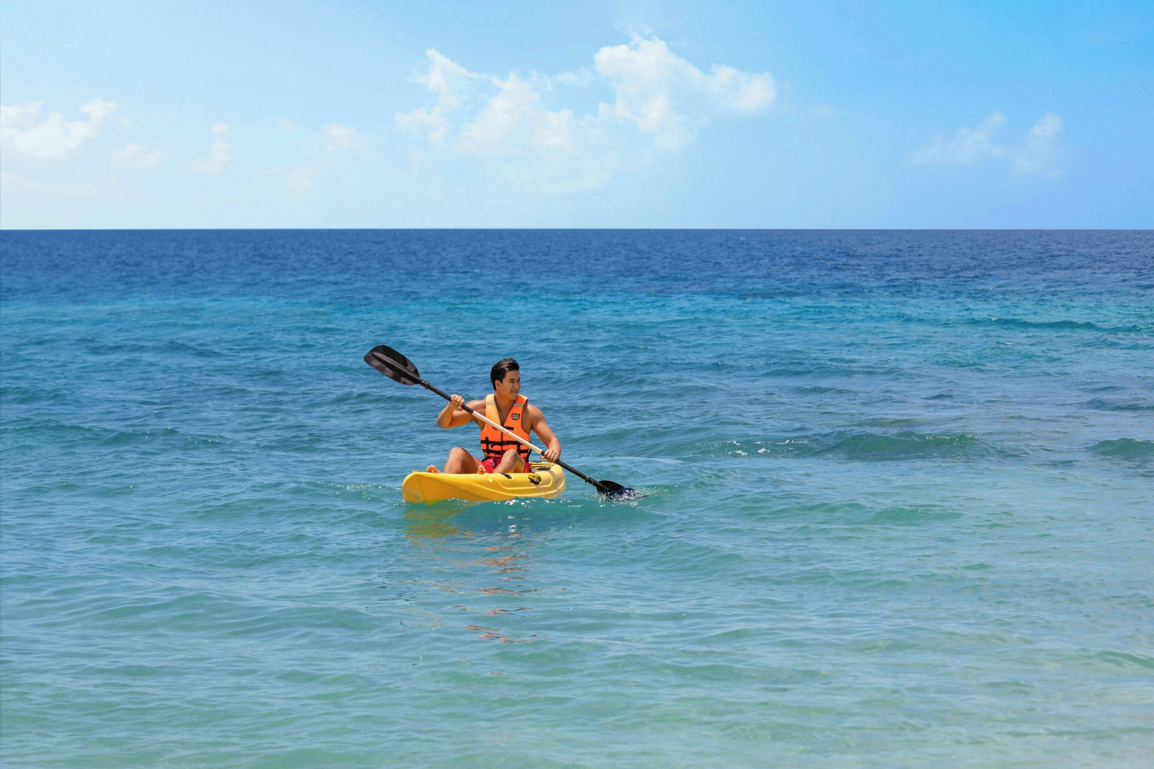 Une personne pratiquant le kayak sur une mer calme.