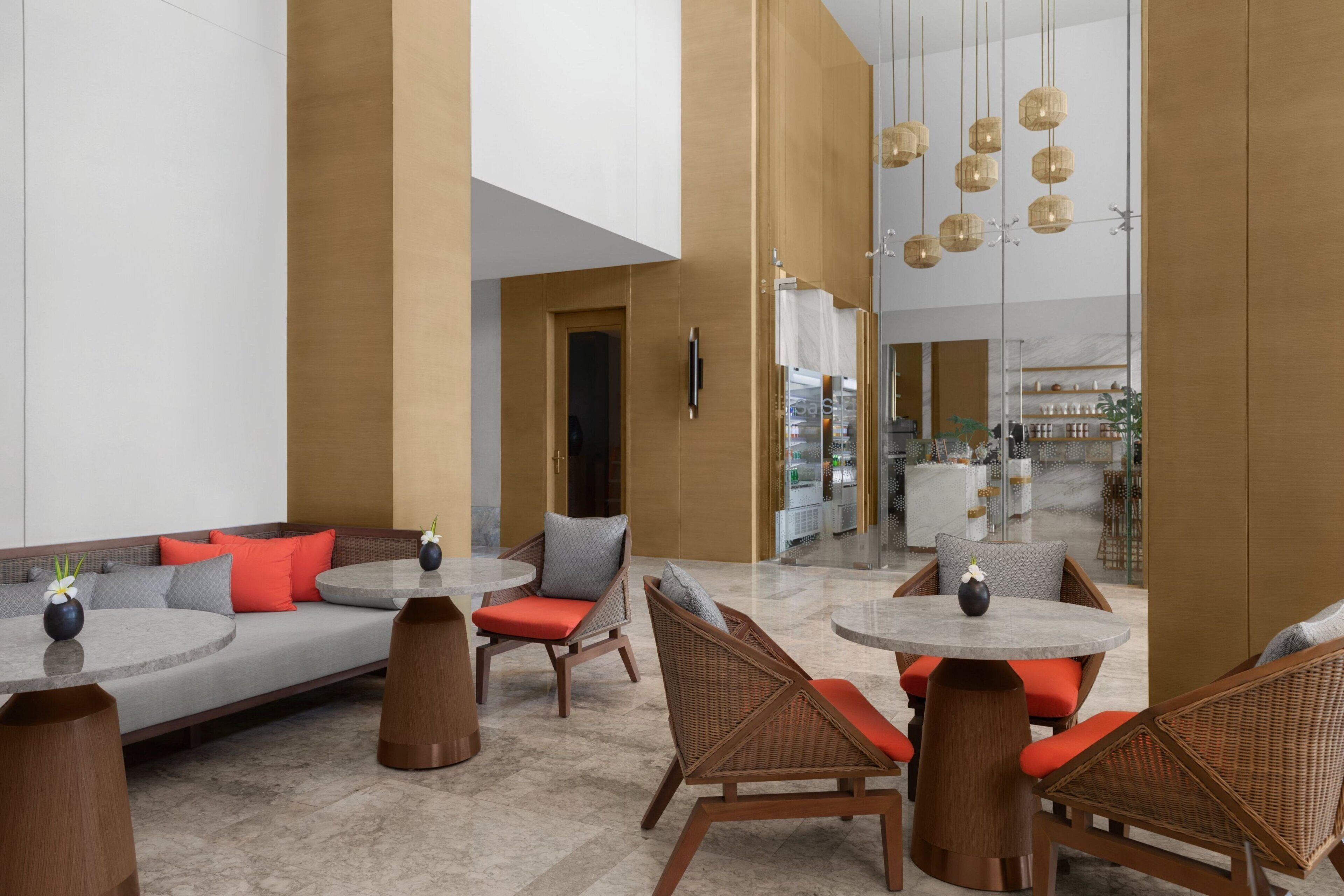A modern indoor space with a mix of seating options including sofas and wicker chairs, arranged around round tables.