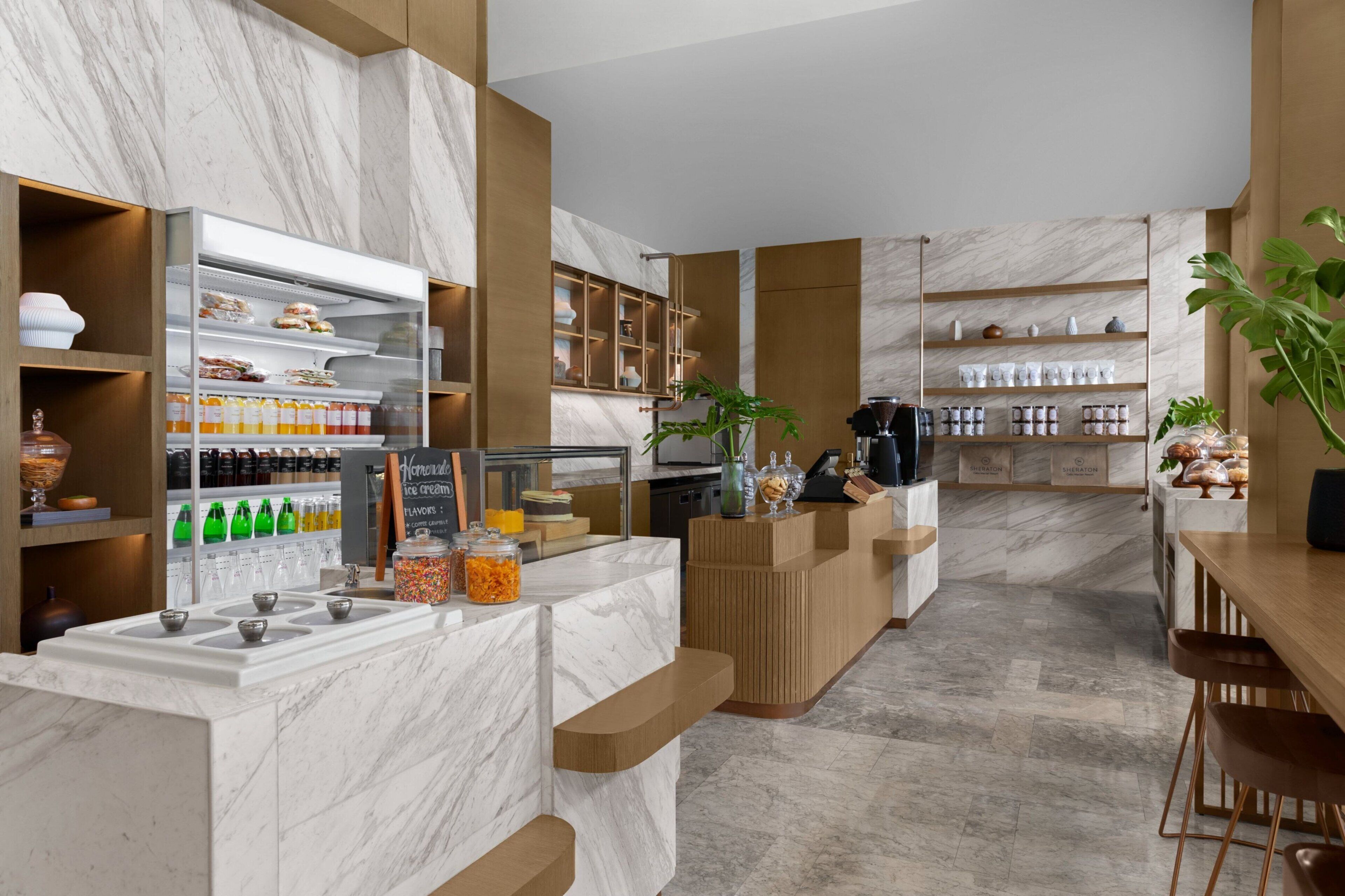 A modern kitchen with marble countertops, wooden shelves, and a coffee station.