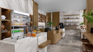 A modern kitchen with marble countertops, wooden shelves, and a coffee station.