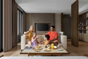 Una sala de estar moderna con un sofá, una mesa de centro con comida y bebidas, y un televisor al fondo.