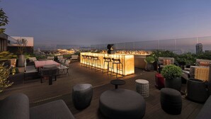 Un bar situé sur le toit, avec un comptoir, un espace salon et des plantes en pot.