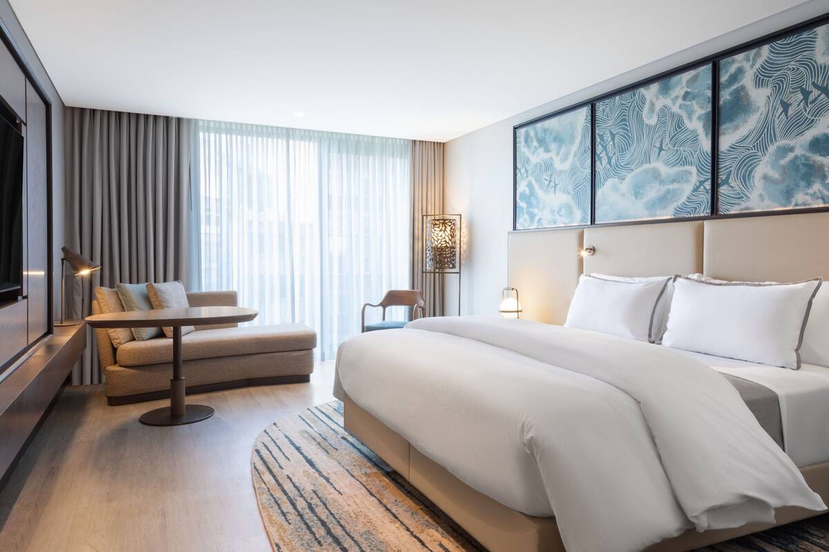 Une chambre d’hôtel moderne avec un grand lit, un canapé, une petite table et un téléviseur.