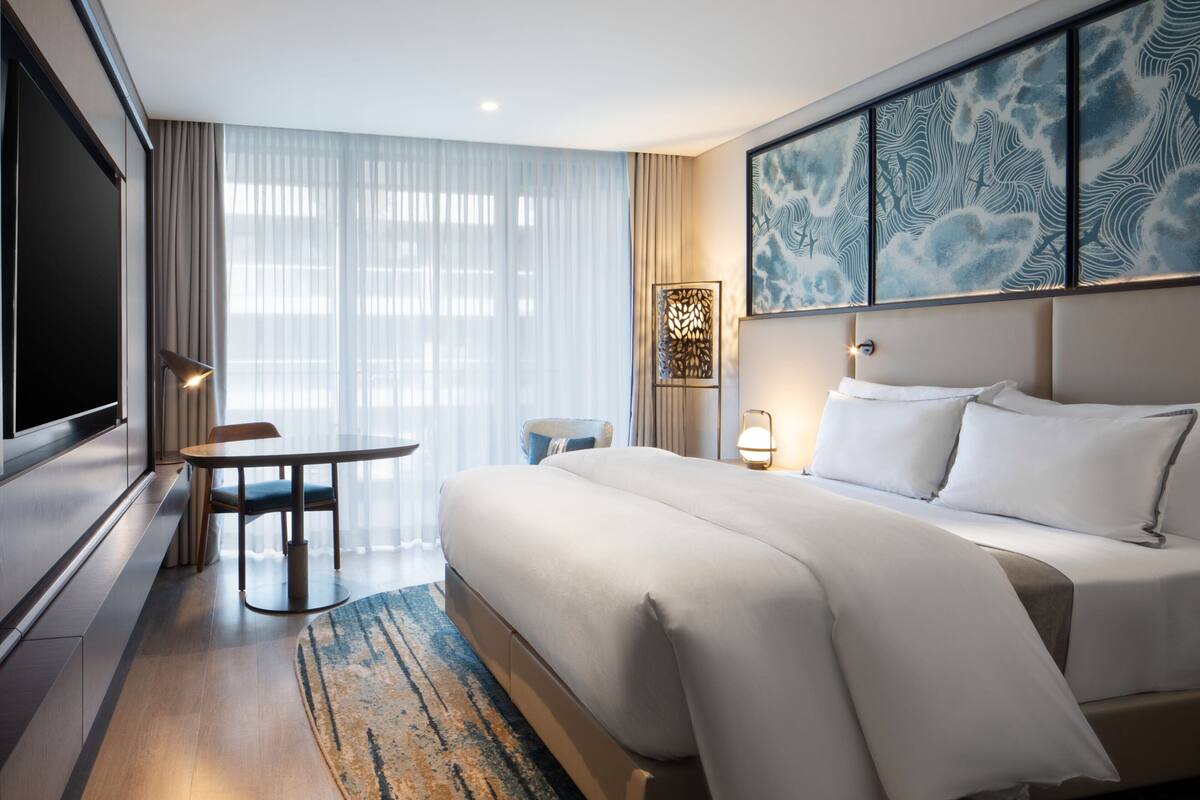 Une chambre d’hôtel avec un grand lit, une table à manger, un téléviseur et un élément décoratif mural.
