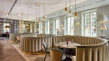 A modern restaurant with a curved seating area, pendant lighting, and large windows.