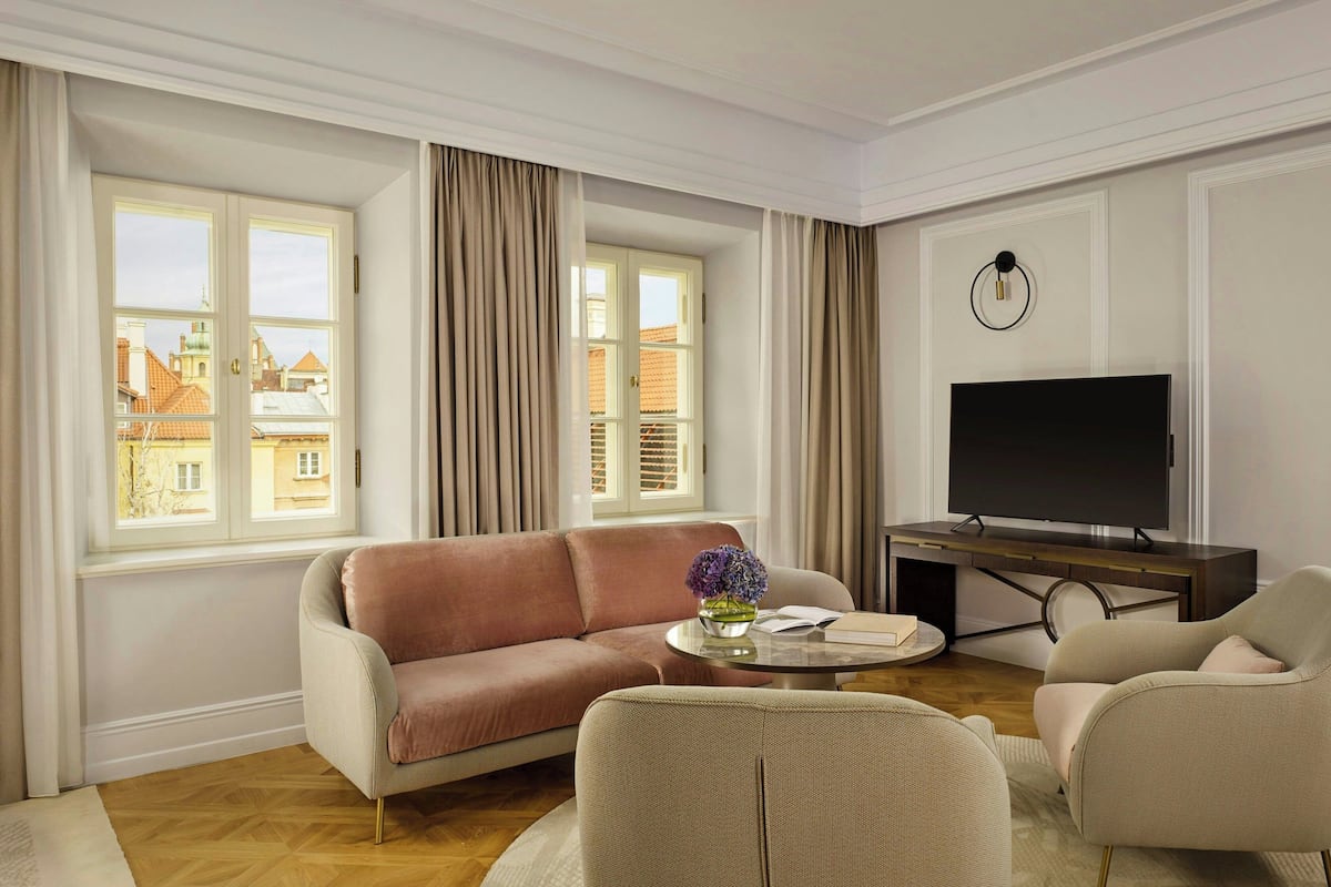 A living room with a sofa, armchairs, a coffee table, and a TV.