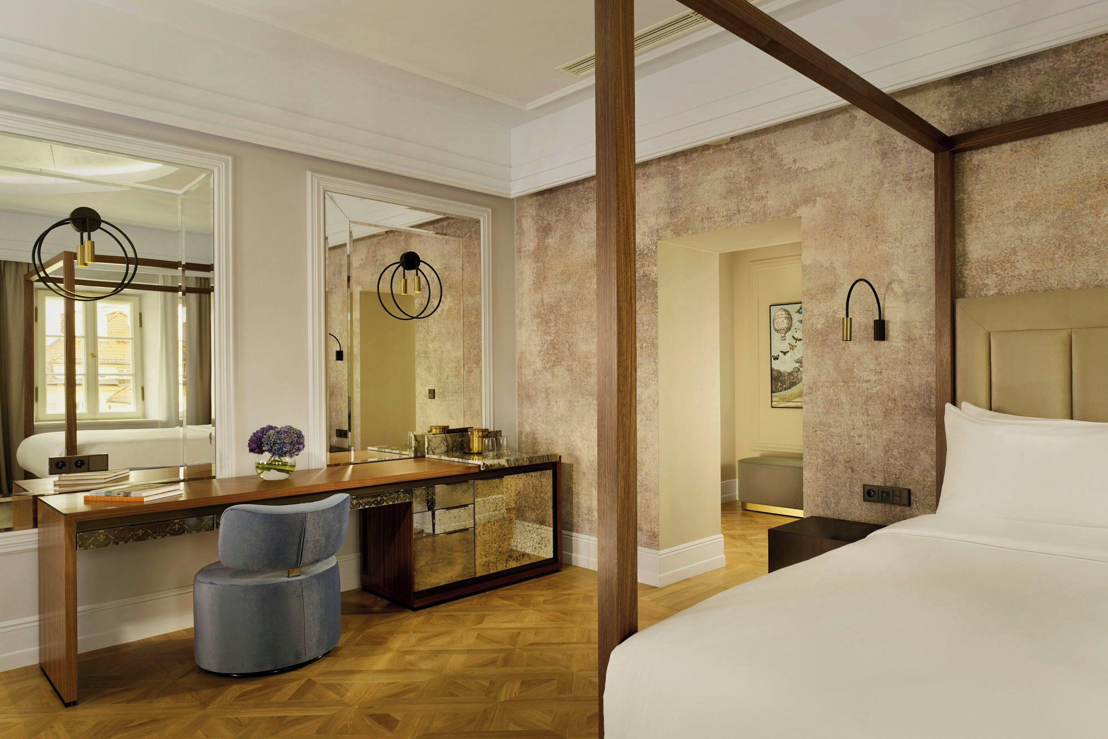 Een hotelkamer met een groot bed, een houten bureau, een stoel en een kaptafel met spiegel.