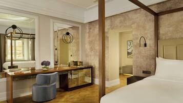 Een hotelkamer met een groot bed, een houten bureau, een stoel en een kaptafel met spiegel.