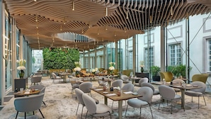 A modern restaurant with a unique ceiling design, large windows, and a green wall. - Hotel Verte, Warsaw, Autograph Collection (Warsaw)