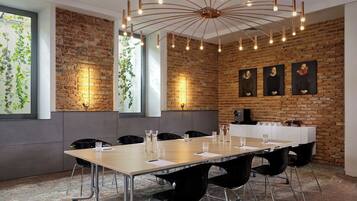 A conference room with a long table, black chairs, a brick wall, and a ceiling light fixture.