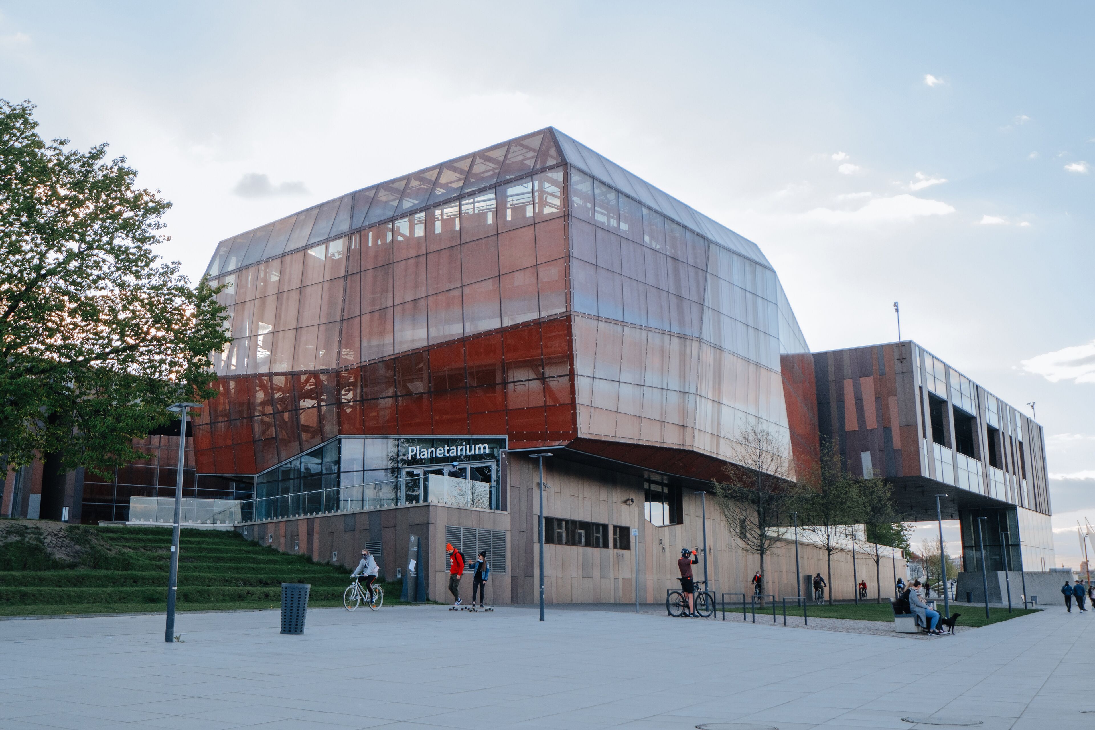 Un bâtiment moderne doté d’une façade en verre et d’une enseigne indiquant « Planétarium ».