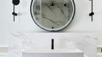 A bathroom with a white marble sink, a black metal frame, and a round mirror with a black frame.