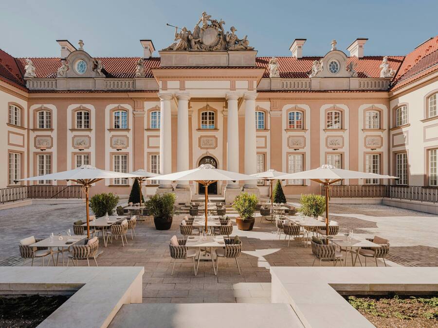 A courtyard with outdoor seating and a large building with classical architecture.