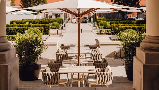 An outdoor seating area with tables and chairs, potted plants, and a view of historic buildings in the background. - Hotel Verte, Warsaw, Autograph Collection (Warsaw)