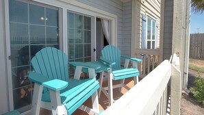 En inglasad veranda med två turkosa Adirondack-stolar och ett vitt bord.