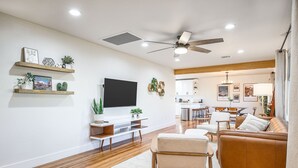 Ein modernes Wohnzimmer mit Flachbildfernseher, Holzregalen und Deckenventilator.